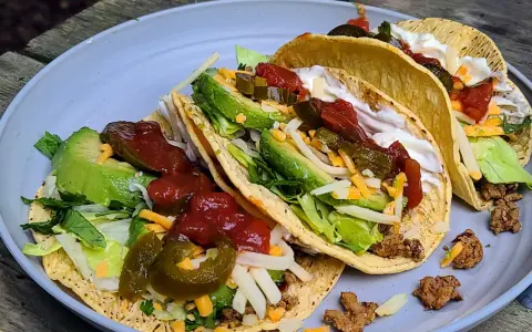 A plate of delicious camp taco with avocado, salsa, cheese, and sour cream, perfect for an outdoor meal.
