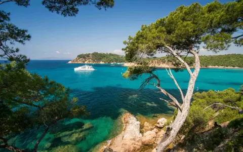 A luxury yacht sails on turquoise waters near a scenic coastline, perfect for a 3-star camping trip in Var.