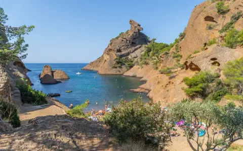 A vibrant scene of camping calanques, with people enjoying the turquoise waters and rocky shores under a clear blue sky.