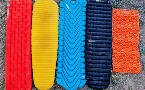 Five camping sleeping pads in red, yellow, blue, black, and orange. The black Nemo Tensor is the quietest sleeping pad for a peaceful night's sleep.
