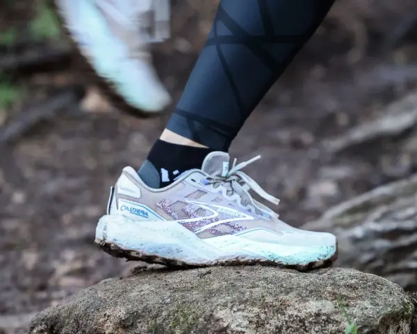 A Brooks Caldera trail running shoe on a rock, illustrating the heel drop for a runner.