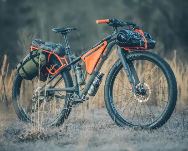 A fully loaded bike camping setup with panniers, frame bags, and handlebar roll, ready for an adventure.