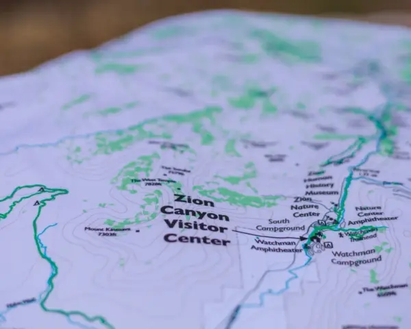 A topographic map of Zion Canyon shows elevation changes with contour lines, highlighting trails, visitor centers, and campgrounds.