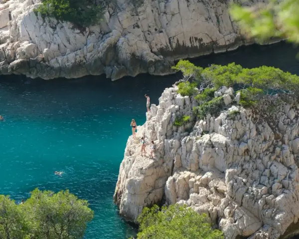 Adventurous swimmers enjoy the turquoise waters of the calanques of Cassis, with some daring to cliff jump from rocky outcrops.