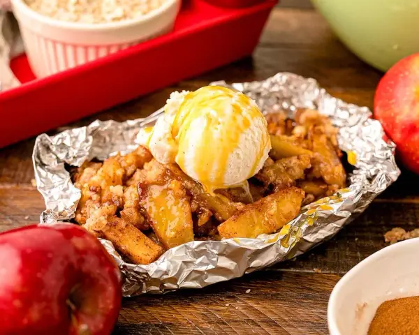 Warm campfire apples, baked in foil, topped with a scoop of vanilla ice cream and drizzled with caramel.