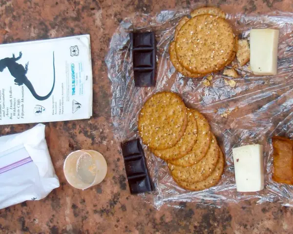 Backpacking lunch ideas no cooking: crackers, cheese, chocolate, dried peas, and jerky laid out on a map.