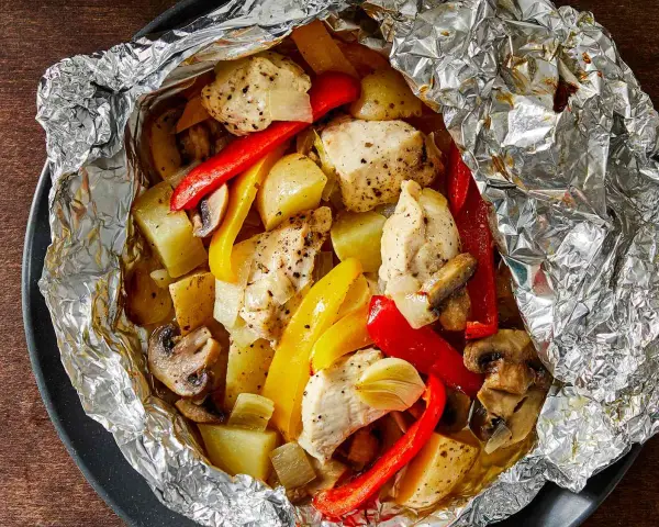 Chicken, potatoes, peppers, and mushrooms cooked in foil. Wondering how long to cook tin foil dinners in fire for this delicious meal?