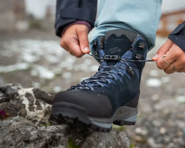 Hands tying laces on a new pair of Han Wag hiking boots, ready for breaking them in on the trail.