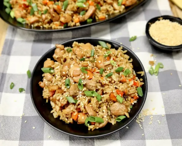 Chicken fried rice, a delicious dish perfect for learning how to cook rice on a Blackstone. Garnished with green onions and sesame seeds.