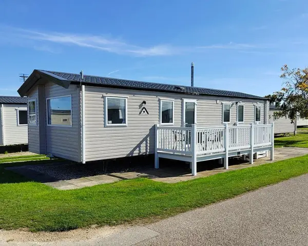 A row of modern mobile homes, perfect for a **location vacances mobil home**, sit under a clear blue sky.