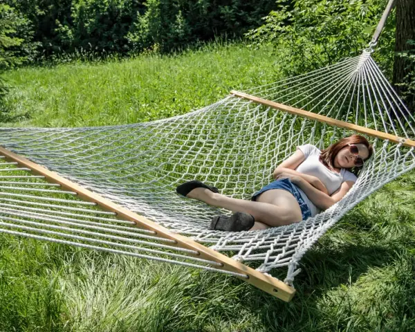 A woman relaxes in a spacious double hammock, enjoying a sunny day outdoors.