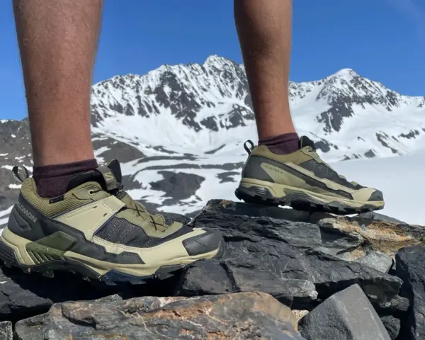 Salomon X Ultra 5 GTX shoes on rocky terrain with snowy mountains in the background. Ready for any adventure.