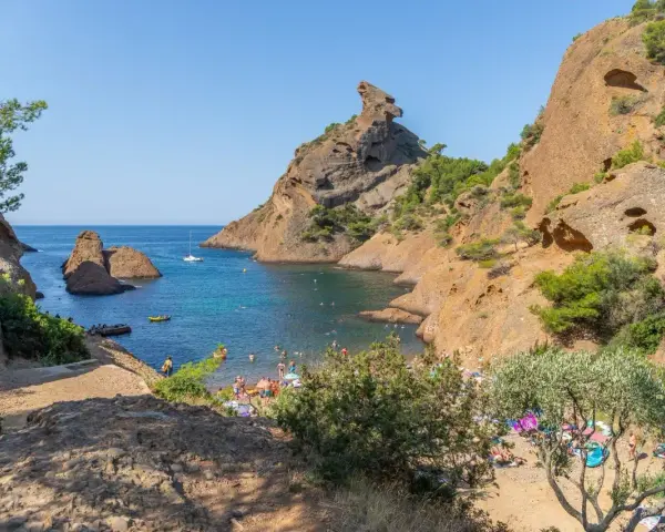 A vibrant scene of camping calanques, with people enjoying the turquoise waters and rocky shores under a clear blue sky.