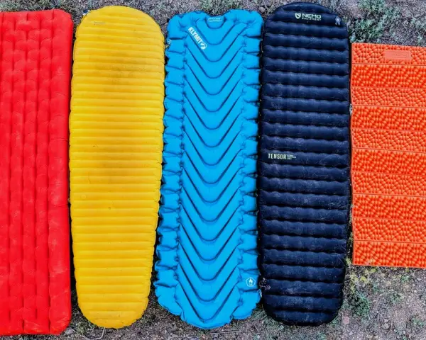 Five camping sleeping pads in red, yellow, blue, black, and orange. The black Nemo Tensor is the quietest sleeping pad for a peaceful night's sleep.