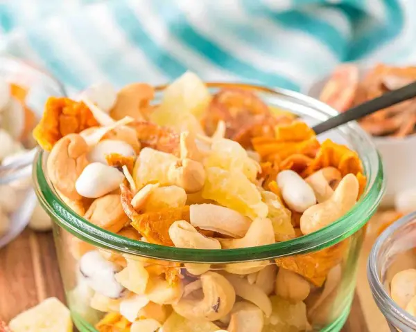 A delicious tropical trail mix recipe with cashews, dried pineapple, and coconut flakes in a glass bowl.