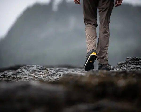 Choosing hiking boots is key for a good trek. This person walks on rocky terrain, showing off their sturdy footwear.