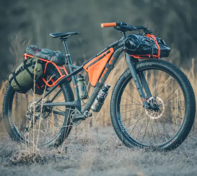 A fully loaded bike camping setup with panniers, frame bags, and handlebar roll, ready for an adventure.