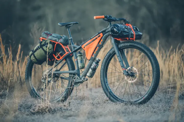 A fully loaded bike camping setup with panniers, frame bags, and handlebar roll, ready for an adventure.