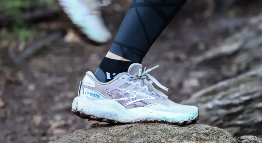 A Brooks Caldera trail running shoe on a rock, illustrating the heel drop for a runner.
