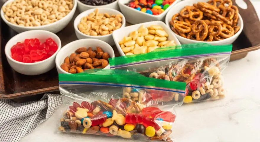 Bags of colorful trail mix bar ingredients: cereal, nuts, pretzels, candy, and dried fruit, ready for snacking.