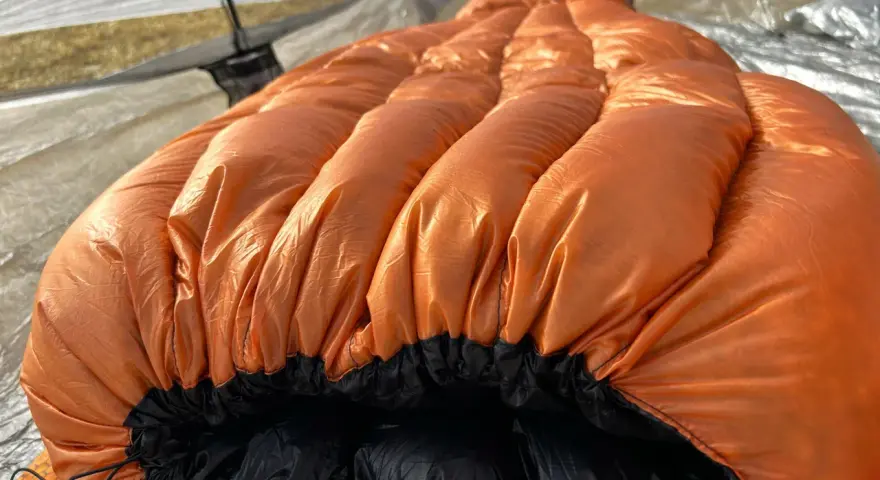 A bright orange sleeping bag with puffy baffles, ready for a cold night. This z pack 20 degree bag is perfect for camping adventures.