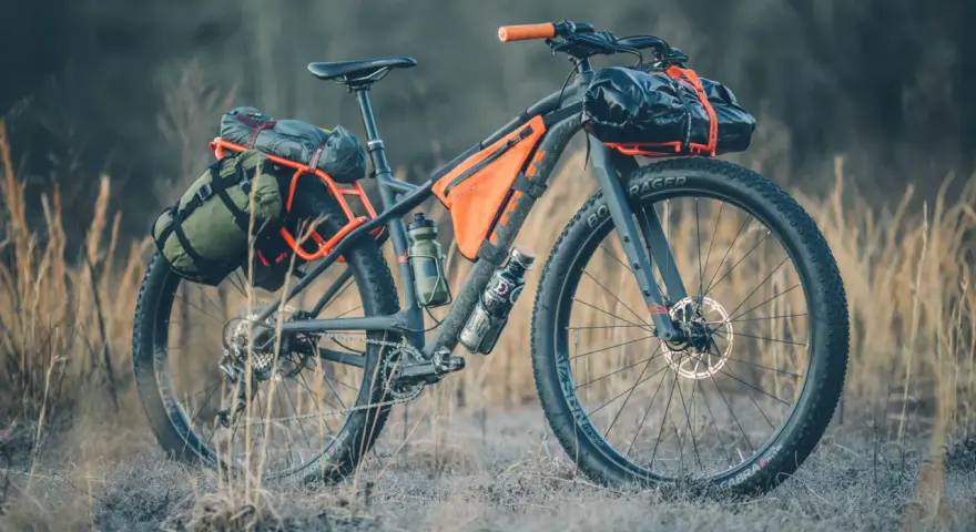 A fully loaded bike camping setup with panniers, frame bags, and handlebar roll, ready for an adventure.