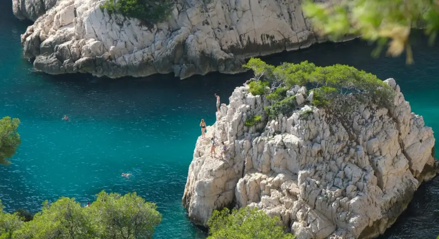 Adventurous swimmers enjoy the turquoise waters of the calanques of Cassis, with some daring to cliff jump from rocky outcrops.