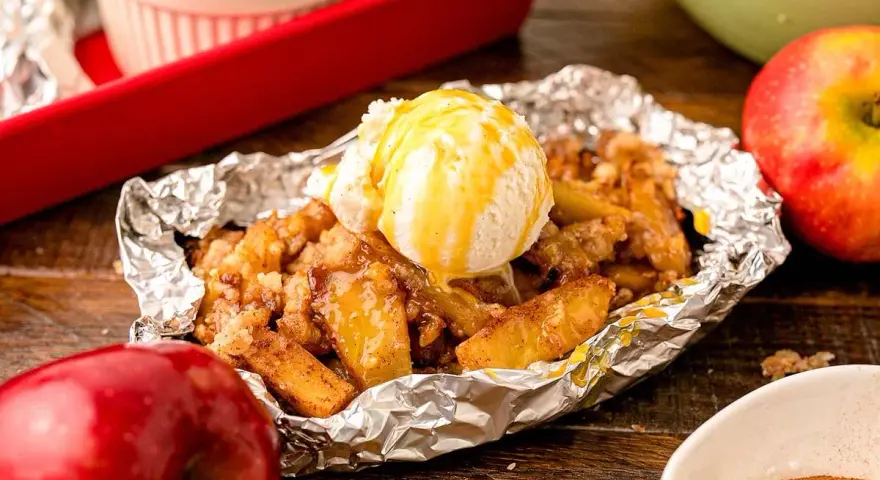 Warm campfire apples, baked in foil, topped with a scoop of vanilla ice cream and drizzled with caramel.