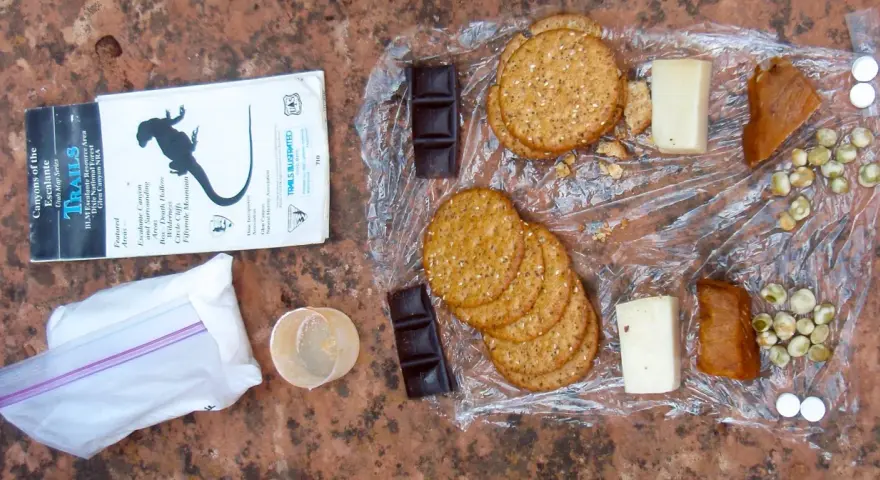 Backpacking lunch ideas no cooking: crackers, cheese, chocolate, dried peas, and jerky laid out on a map.