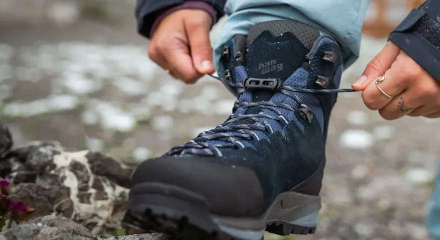 Hands tying laces on a new pair of Han Wag hiking boots, ready for breaking them in on the trail.