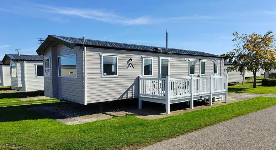 A row of modern mobile homes, perfect for a **location vacances mobil home**, sit under a clear blue sky.