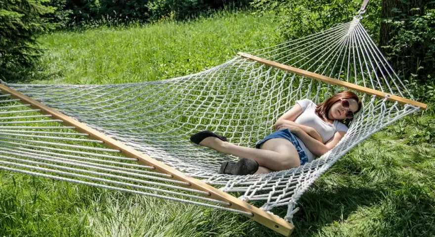 A woman relaxes in a spacious double hammock, enjoying a sunny day outdoors.