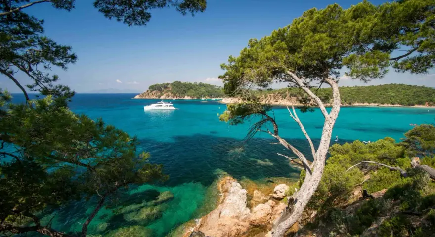 A luxury yacht sails on turquoise waters near a scenic coastline, perfect for a 3-star camping trip in Var.