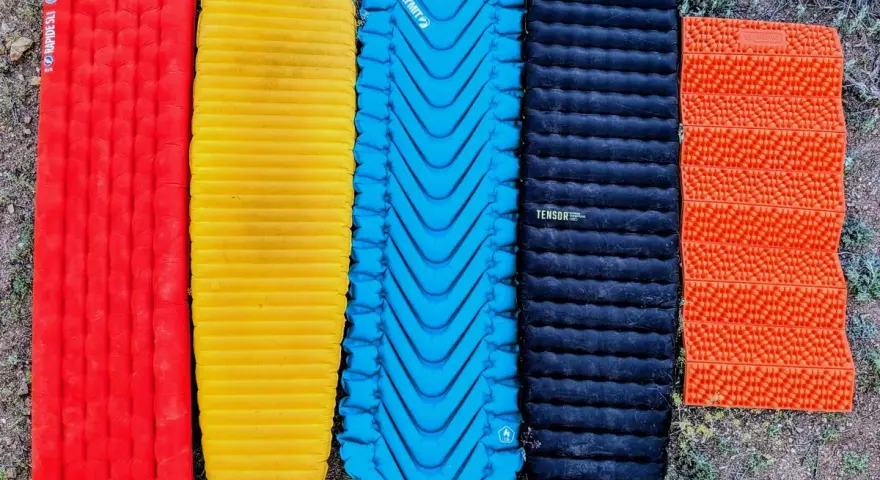 Five camping sleeping pads in red, yellow, blue, black, and orange. The black Nemo Tensor is the quietest sleeping pad for a peaceful night's sleep.
