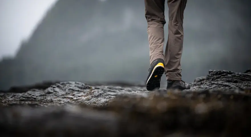 Choosing hiking boots is key for a good trek. This person walks on rocky terrain, showing off their sturdy footwear.