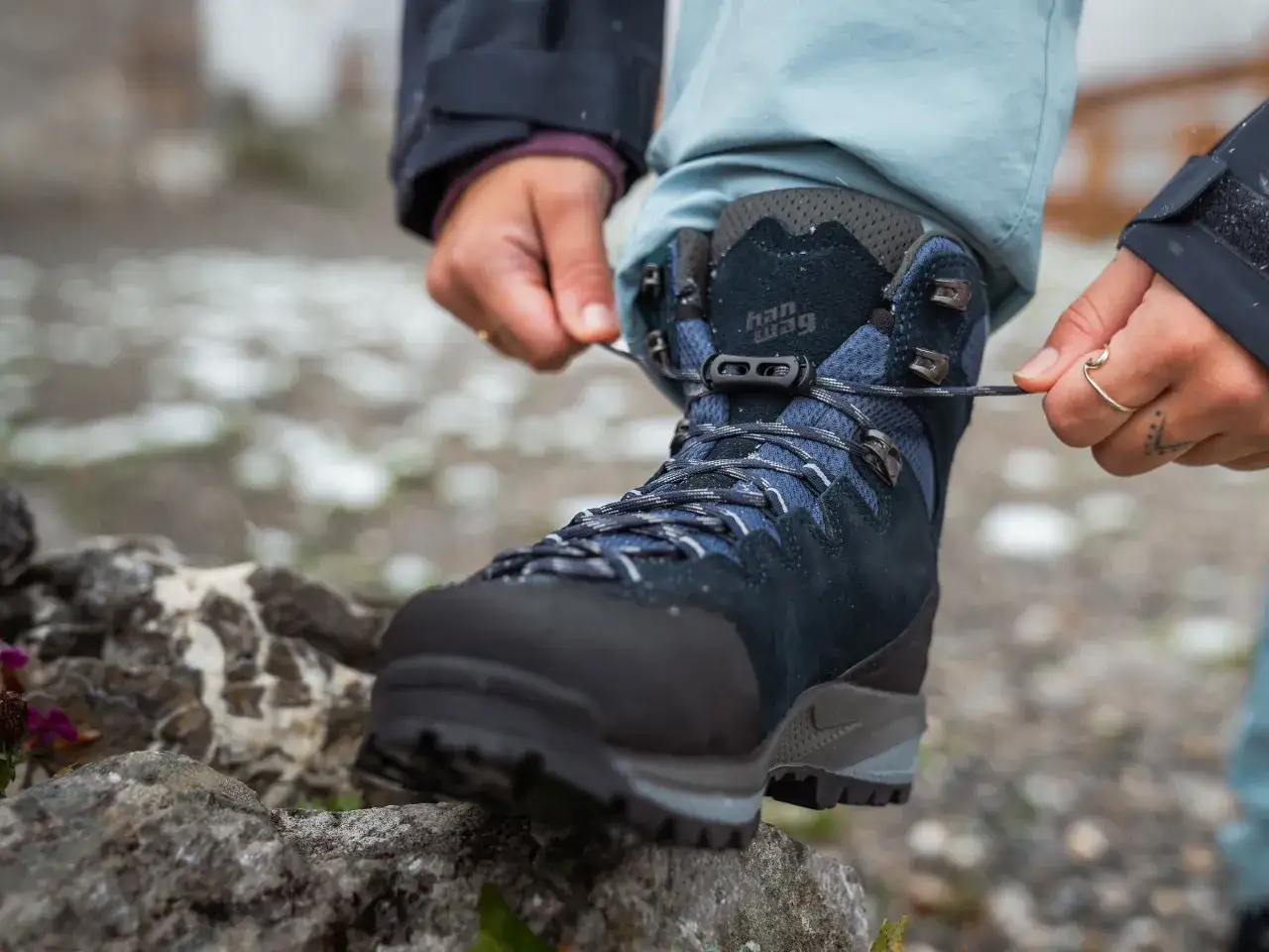 Hands tying laces on a new pair of Han Wag hiking boots, ready to break them in on the trail.