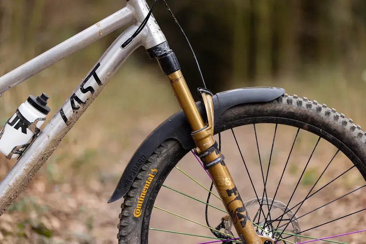 A muddy mountain bike with a water bottle, ready for biking in the rain.