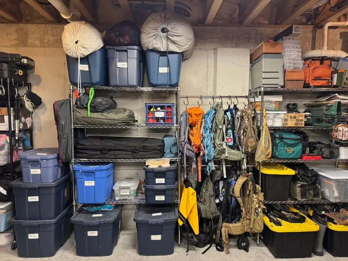 Organized gear for camping packing hacks: backpacks, tents, sleeping bags, and labeled bins.