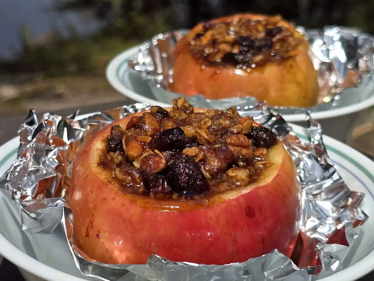 Two delicious campfire apples, baked in foil and stuffed with a sweet, nutty filling, ready to be enjoyed outdoors.