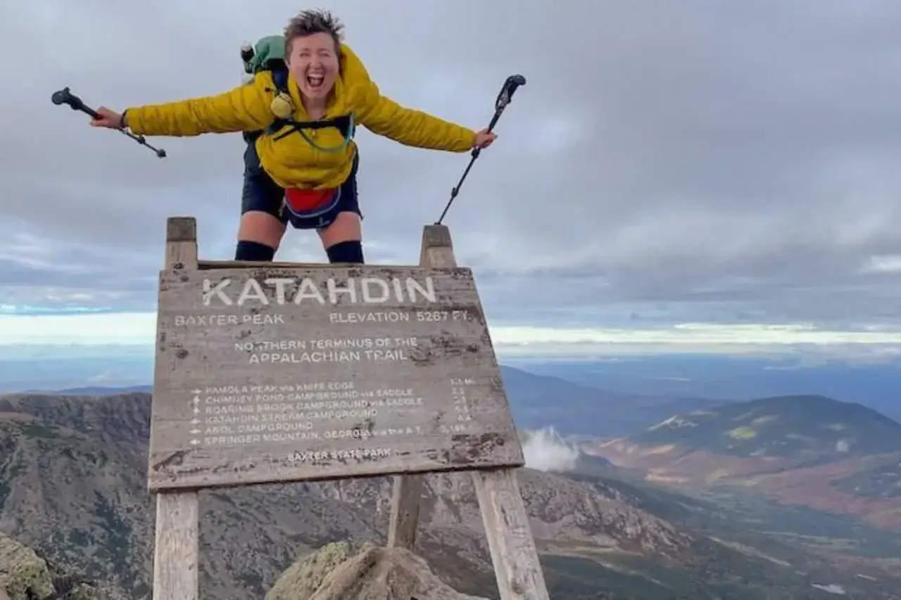 Triumphant hiker at Katahdin, Northern Terminus of the Appalachian Trail. This is the reward for how to train for a long-distance hike!