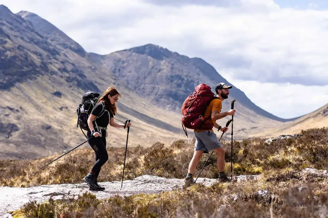 Two hikers with large backpacks trek through a mountainous landscape, showcasing the spirit of thru hiking vs backpacking.