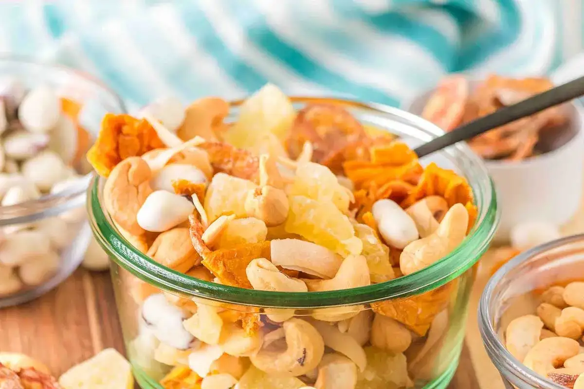 A delicious tropical trail mix recipe with cashews, dried pineapple, and coconut chips in a glass bowl.