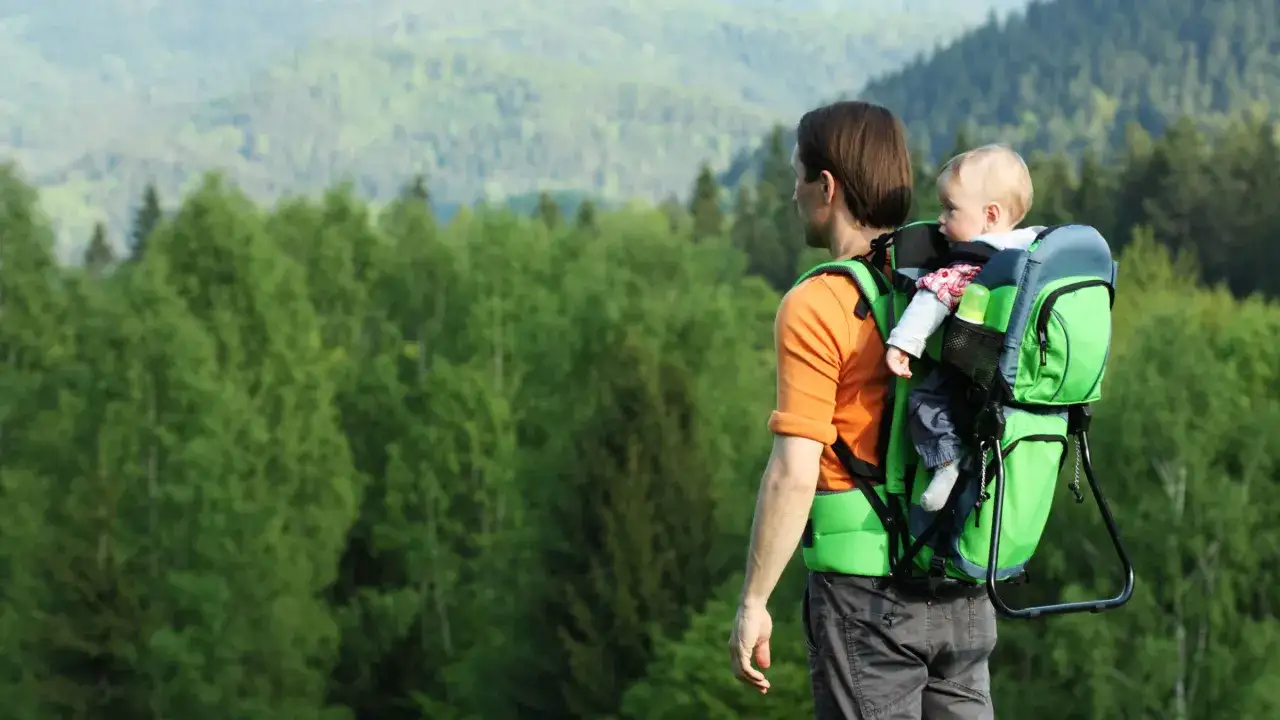 Father carries baby in Osprey Poco Plus, enjoying a scenic hike. The carrier's weight limit is suitable for this adventure.