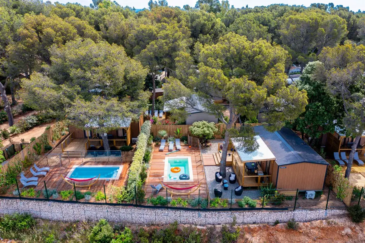 A serene location mobil home Provence, featuring private pools, hammocks, and lounge chairs nestled amongst lush pine trees.