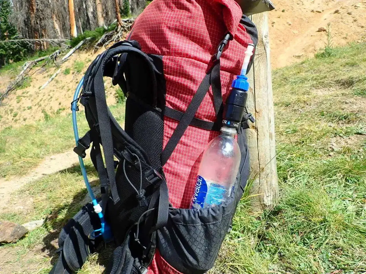 Backpack with water filter and bottle attached. This setup helps answer how much water to bring backpacking, as you can refill from natural sources.