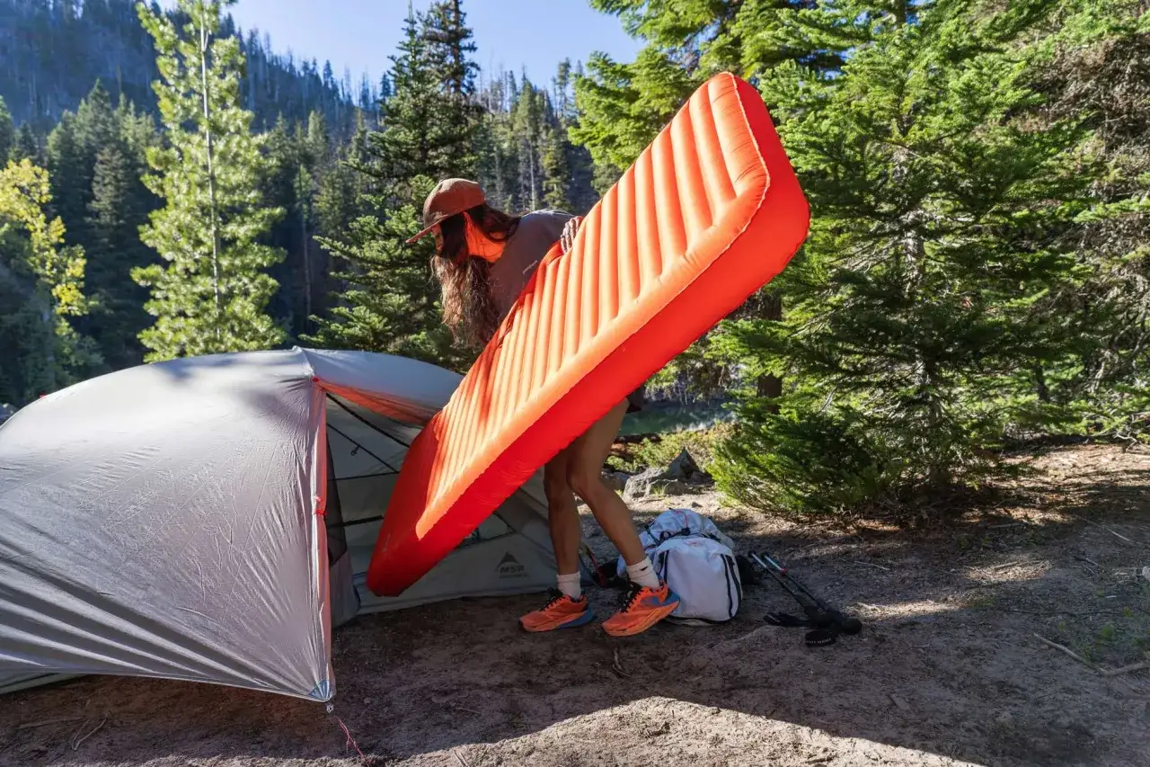 Setting up camp with a bright orange Therm-a-Rest NeoAir XLite sleeping pad.