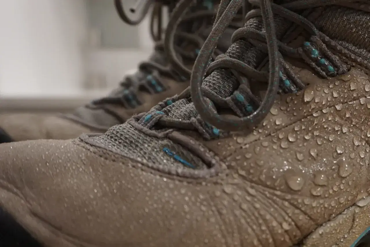 Water droplets bead on tan hiking boots, showing how to waterproof hiking boots for your next adventure.