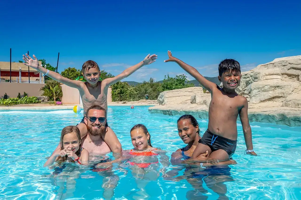 Family fun camping en Provence avec piscine! Kids on shoulders, splashing in the sun.