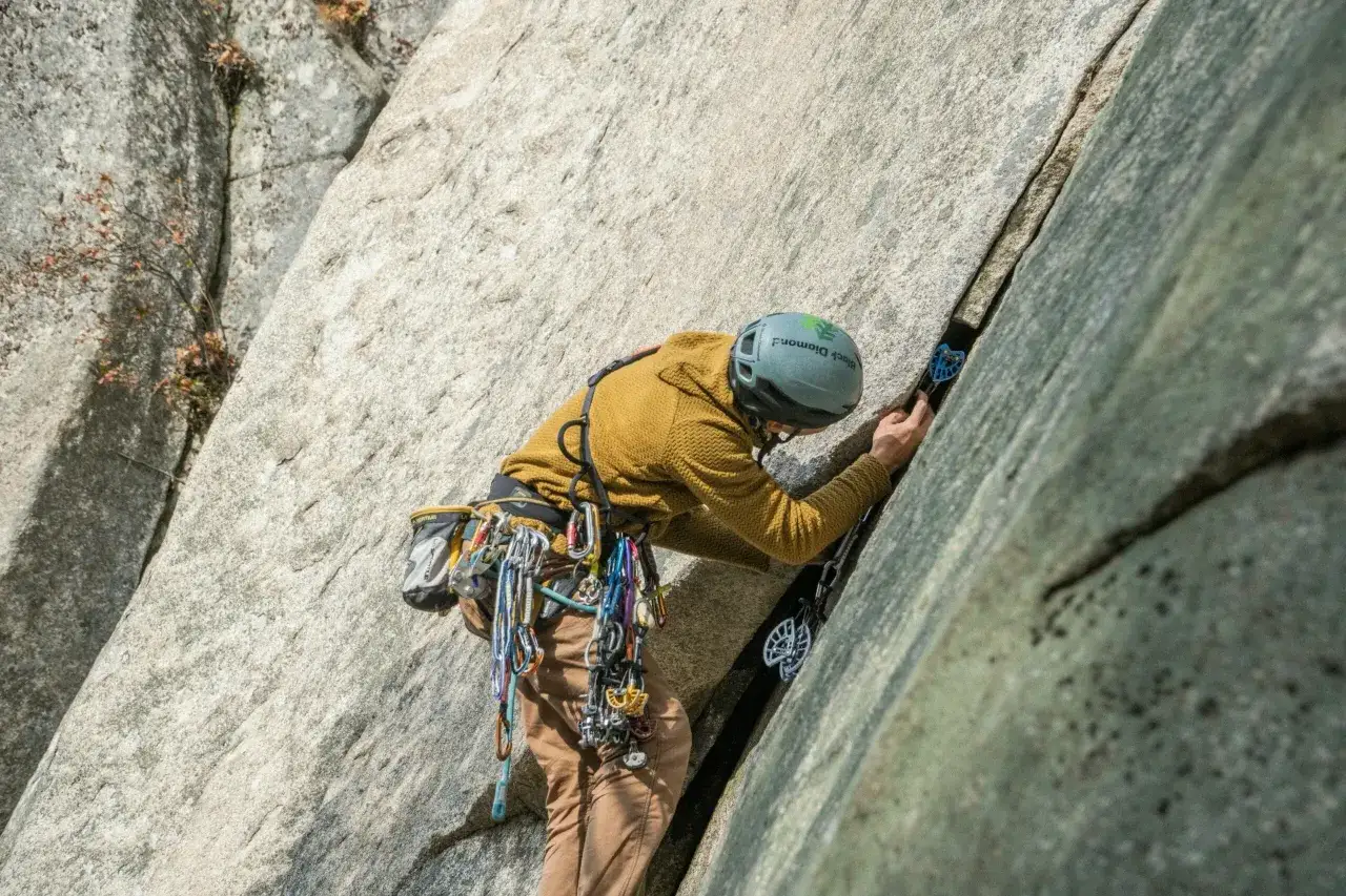A climber ascends a granite face, using gear for protection. This image showcases the skill and equipment involved in various types of rock climbing.