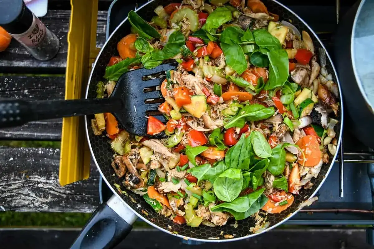 A delicious stir-fry with chicken, carrots, zucchini, and peppers, perfect for camp stove recipes. Fresh basil tops this colorful dish.